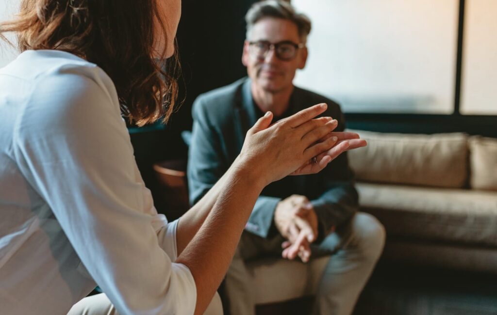 seated woman gestures while talking to seated man 